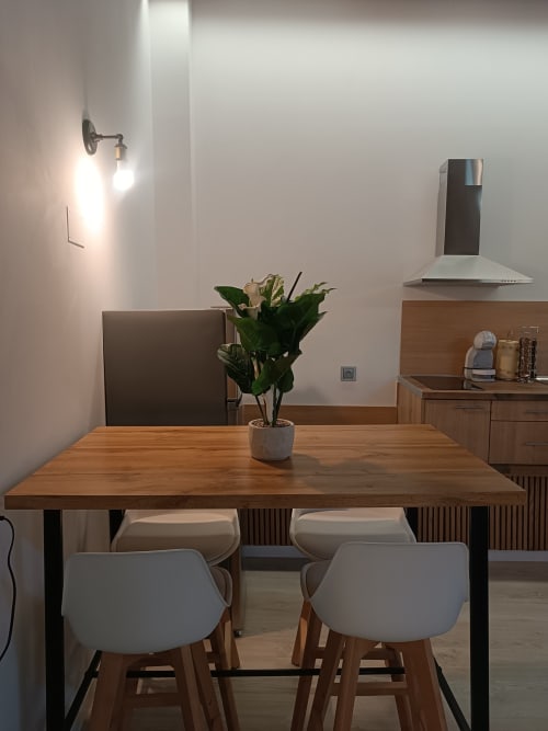 Comedor moderno en apartamento de Ávila con mesa de madera, sillas claras, planta decorativa y equipamiento de cocina