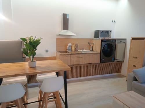 Zona de cocina-comedor moderna en Apartamentos Turísticos Ávila con muebles de madera, electrodomésticos de acero inoxidable, mesa de comedor