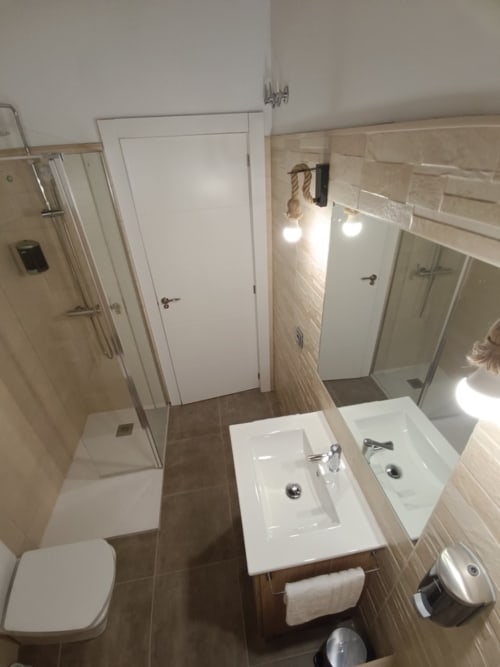 Baño moderno en apartamento de Ávila con doble lavamanos, ducha y accesorios de inodoro