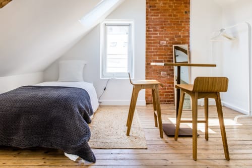 Chambre loft moderne aux Filles du Bord de Mer avec mobilier en bois, murs de brique apparente et lumière naturelle par puits de lumière