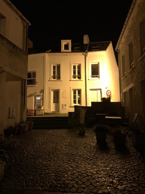 Illuminated cottage at Les Filles du Bord de Mer in Port-en-Bessin, Normandy, nighttime exterior view