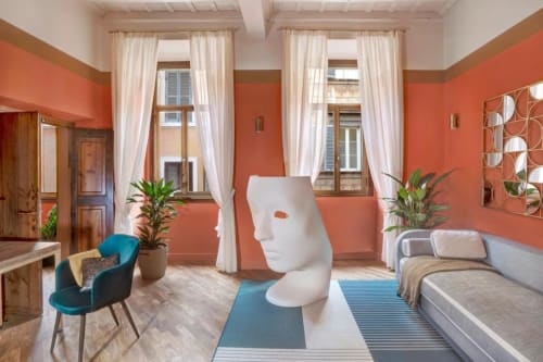 Suite Luxury Trevi House Roma con pareti color corallo, scultura bianca moderna, poltrona turchese e arredi contemporanei.