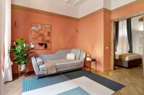 Suite moderna della Luxury Trevi House Roma con pareti color corallo, divano grigio, arte geometrica e vista sulla camera da letto