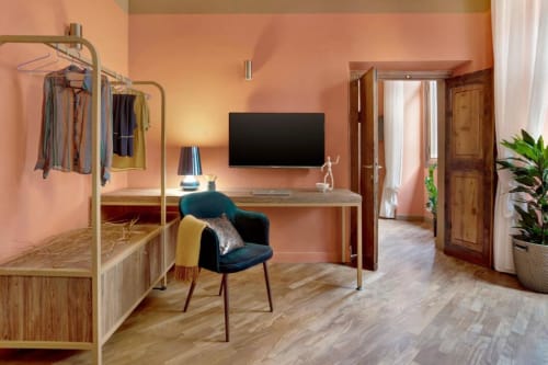 Suite lussuosa a Trevi House Roma con pareti color corallo, scrivania, TV, portabiti e arredi moderni