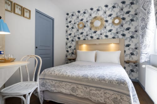 Chambre simple standard à l'Hôtel De Lion Sur Mer avec papier peint à motifs, lit queen-size avec oreillers blancs, bureau et mobilier moderne