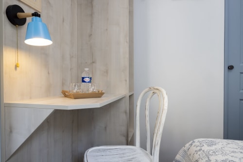 Espace de travail moderne à l'hôtel De Lion Sur Mer avec lampe murale bleue, bureau blanc et chaise blanchie