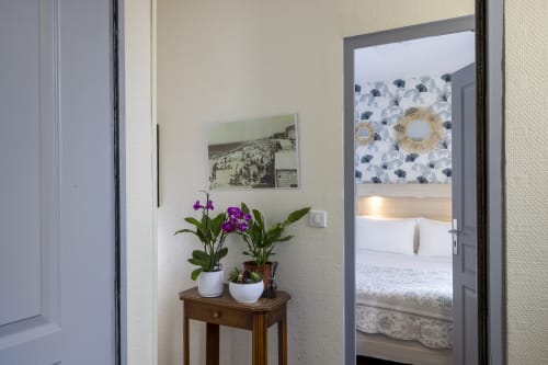 Entrée de chambre standard de l'Hôtel De Lion Sur Mer avec fleurs violettes en pot et décoration thématique côtière