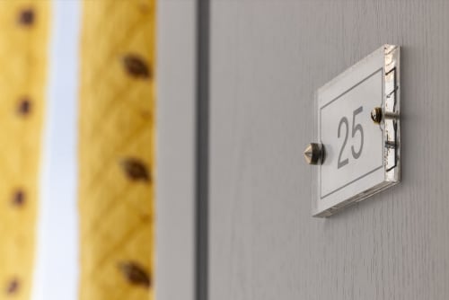 Pancarte du numéro 25 sur mur gris à l'Hôtel De Lion Sur Mer à Lion-sur-Mer, France