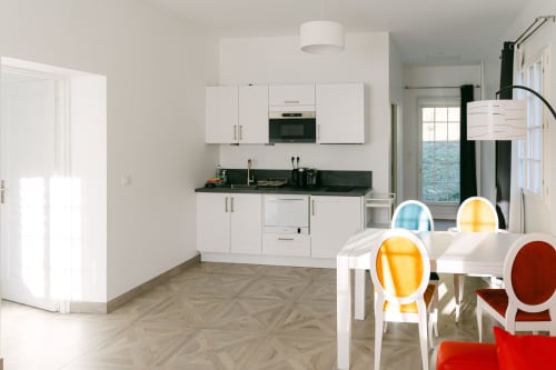 Cuisine moderne aux armoires blanches et plan de travail noir, salle à manger avec chaises colorées, Appartement Toulouse au Domaine