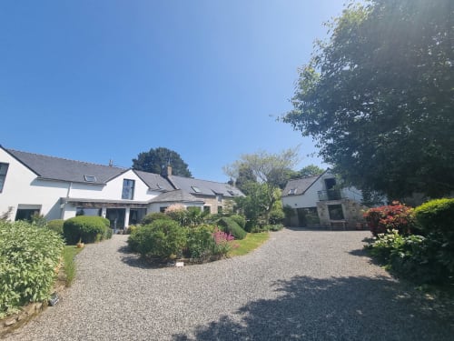 Vue d'ensemble du jardin de Ty Coz Breizh, situé en Bretagne Sud, au Pays de Lorient, avec une belle terrasse verdoyante et une dépendance charmante. L'espace offre un cadre paisible et naturel, parfait pour les hôtes souhaitant se détendre en pleine nature