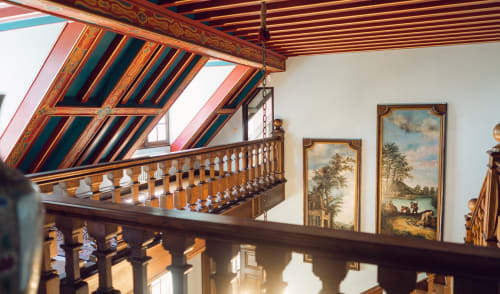Ornate wooden staircase and balcony with decorative ceiling at Domaine de Bize Mirepoix manor in Ariège