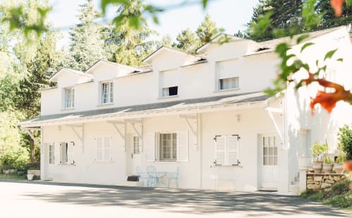 Modern white apartment building at Domaine de Bize in Mirepoix, Ariège, with terrace seating and tree-lined surroundings.