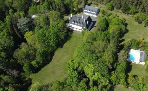 Aerial view of Domaine de Bize manor surrounded by lush green forests and manicured grounds in Mirepoix, Ariège