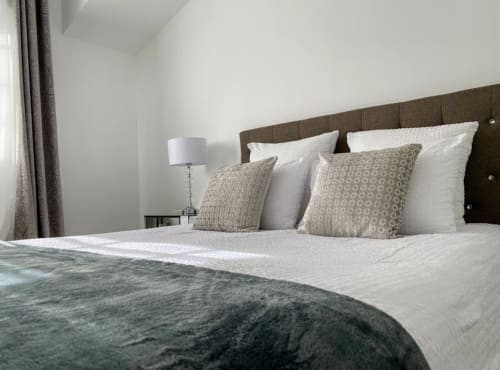 Modernes Schlafzimmer mit braunem Kopfteil, weißer Bettwäsche und dekorativen Kissen im Domaine de Bize, Mirepoix