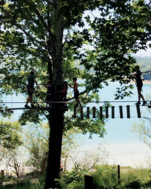 Des clients naviguent sur un parcours de cordes en hauteur dans les arbres du Domaine de Bize, activité d'aventure à Mirepoix Ariège
