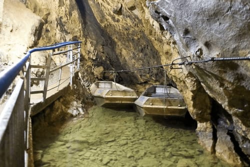 Pasaje subterráneo con botes, barandillas metálicas y formaciones de roca caliza en alojamiento francés