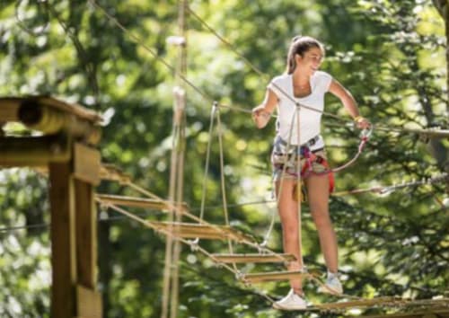 Young girl navigating rope course at Domaine de Bize Mirepoix, adventure activity in Ariège Occitanie