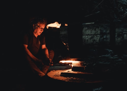 Man tending campfire at night in Mirepoix countryside retreat