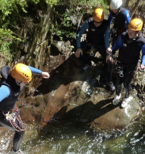 Group canyoning adventure in Ariège near Mirepoix with guides in wetsuits and helmets exploring rocky creek