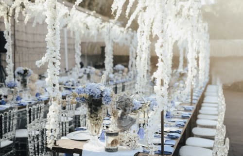 Mesa elegante de recepción nupcial en Domaine de Bize Mirepoix con cascadas florales blancas, acentos azules y disposición formal