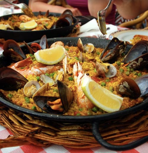 Paella tradicional con mariscos, mejillones y limón servida en sartén negra en Domaine de Bize Mirepoix