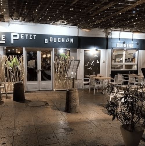 Fachada del restaurante Le Petit Bouchon iluminada por la noche con asientos al aire libre en Mirepoix