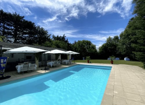 Piscine étincelante avec terrasse, parasols blancs et coin repas au Domaine de Bize Mirepoix en Ariège, France