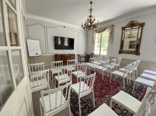 Elegant seminar room at Domaine de Bize with white chairs, red carpet, and crystal chandelier in Mirepoix
