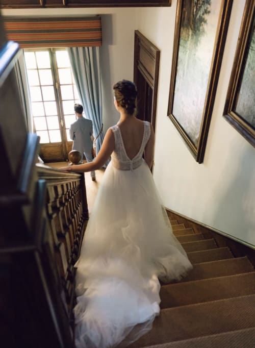 Braut im weißen Kleid ersteigt die Treppe des Herrenhauses Domaine de Bize Mirepoix in Ariège