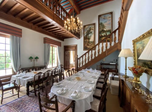 Elegantes Esszimmer in der Domaine de Bize Mirepoix mit Holzbalken, Kronleuchter, formal gedecktem Tisch und Treppe.