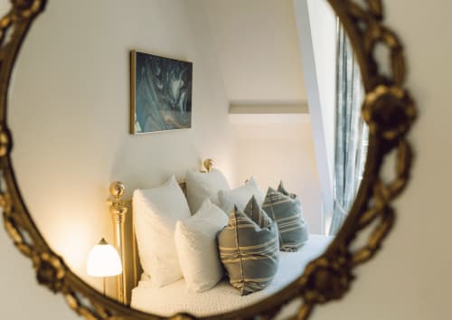Elegant bedroom reflection in ornate mirror at Domaine de Bize Mirepoix, featuring white bedding and striped pillows