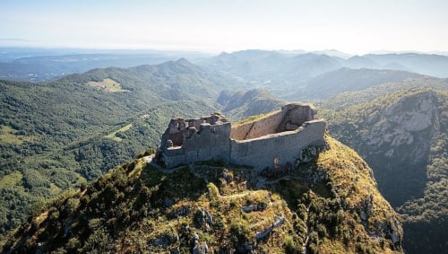 Ruines d'un château médiéval perchées sur un pic rocheux dominant les montagnes forestières de l'Ariège, France