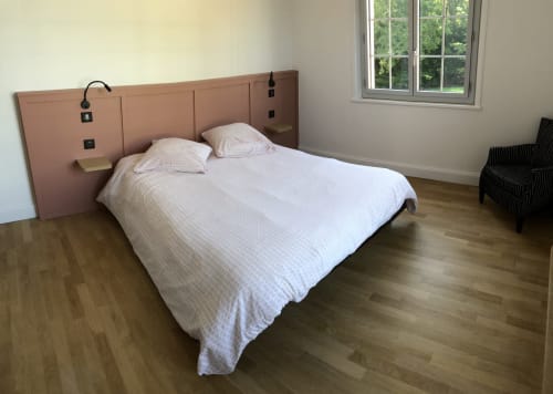 Chambre moderne à La Conciergerie Biarritz avec tête de lit terracotta, literie blanche, parquet et vue sur le jardin.