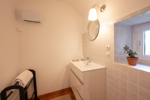 Modern bathroom at Espace Ker Gana in Plourin with white vanity, wall mirror, and tiled walls in Maison Aster room.