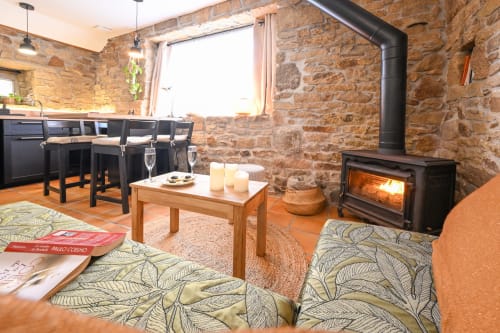 Cozy stone-walled living room at Espace Ker Gana B&B in Plourin with fireplace, seating, and kitchenette