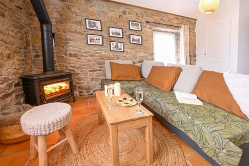 Cozy living room at Espace Ker Gana in Plourin with wood stove, stone walls, and comfortable seating
