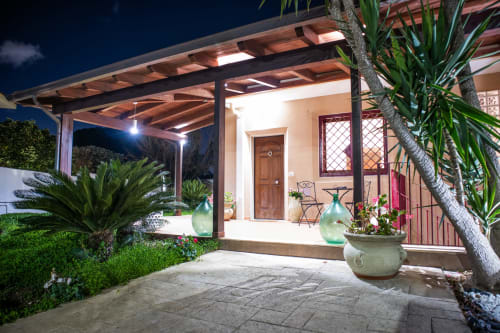 Il patio serale di Villa Il melograno con pergolato, piante in vaso e ingresso illuminato a Bari
