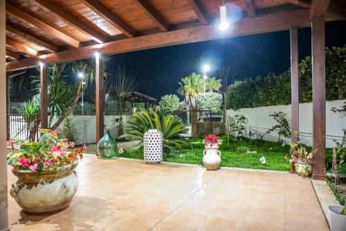 Vista serale del giardino di Villa Il melograno, villa vacanzale a Bari con terrazza, fiori in vaso e paesaggio illuminato