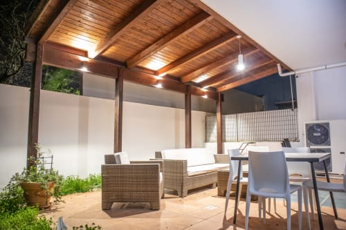 Terrazza coperta moderna della villa di Bari con sedute in rattan, tavolo da pranzo e illuminazione ambientale sotto soffitto in legno