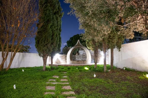 Cortile illuminato di Villa Il melograno a Bari con arco moderno bianco, prato curato e cipressi