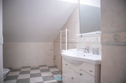 Bagno moderno con lavabo bianco, scaldasalviette e pavimento a scacchiera a Villa Il melograno, Bari