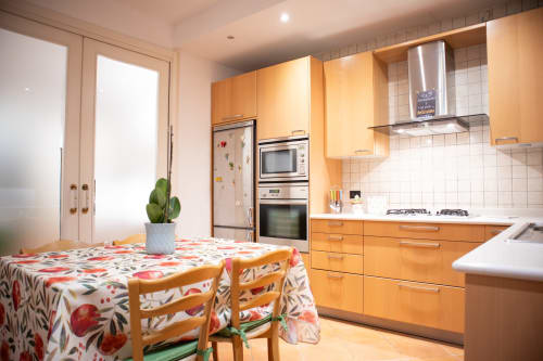 Luminosa zona cucina-pranzo di Villa Il melograno a Bari con mobili in legno, elettrodomestici in acciaio inox e tavolo colorato