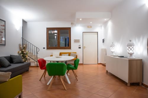 Zona living di una villa moderna a Bari con tavolo rotondo bianco, sedie colorate e vista sul giardino
