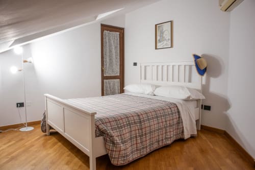 Camera da letto spaziosa con letto in legno bianco, biancheria a quadri e pavimenti in legno a Villa Il melograno a Bari, Italia