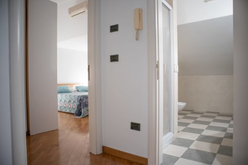 Corridoio di Villa Il melograno a Bari con pavimenti in legno, pareti bianche e porte che conducono alla camera da letto e al bagno