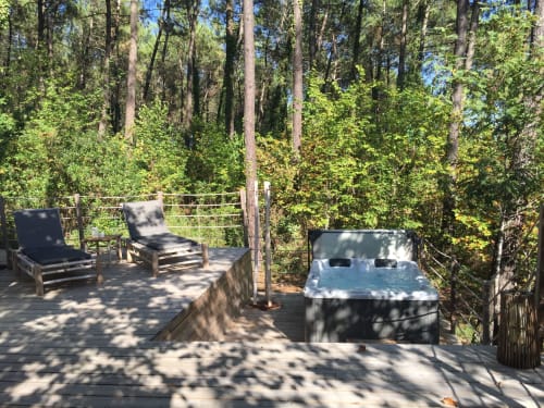 Terrasse en bois avec des éclairages intégrés dans les marches. Ses bains de soleil en bambou et ses coussins gris seront parfaits pour vous prélasser au soleil après un bain dans votre jacuzzi privatif chauffé à 38 degrés. La terrasse est aussi équipée d'un portemanteau pour vos peignoirs doux. 