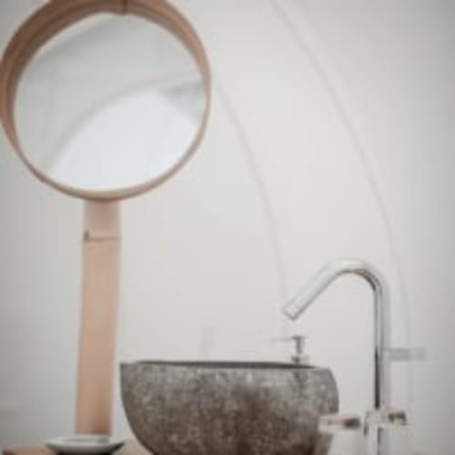 Vasque taillée dans une pierre naturelle dans la salle de bain de la bulle cabernet. L'élégance et l'originalité de cette vasque ajoutent une touche à cette expérience singulière et luxueuse. Le miroir encerclé dans du bambou ajoute aussi une touche de douceur au design de cette suite parentale.