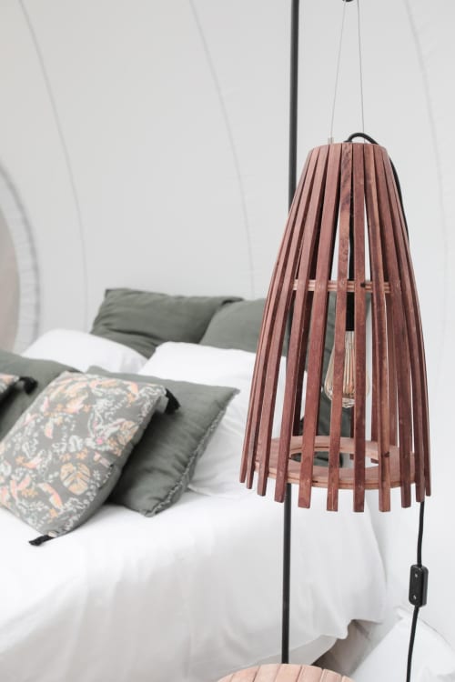 Décoration épurée dans une bulle insolite à bordeaux dans les tons bleu avec un diffuseur de parfum au premier plan. Le lit est bercé d'une lumière douce. On aperçoit des ombres formées par le soleil et les feuilles de la foret sur la bulle insolite.