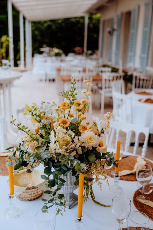 Table de réception élégante au Domaine de Bize avec centre de table floral jaune et blanc, bougies et couverts