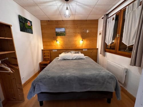 Chambre cosy en bois du gite le Chalain aux Gîtes Des Planchettes à Marigny avec lit double, éclairage chaleureux et charme rustique